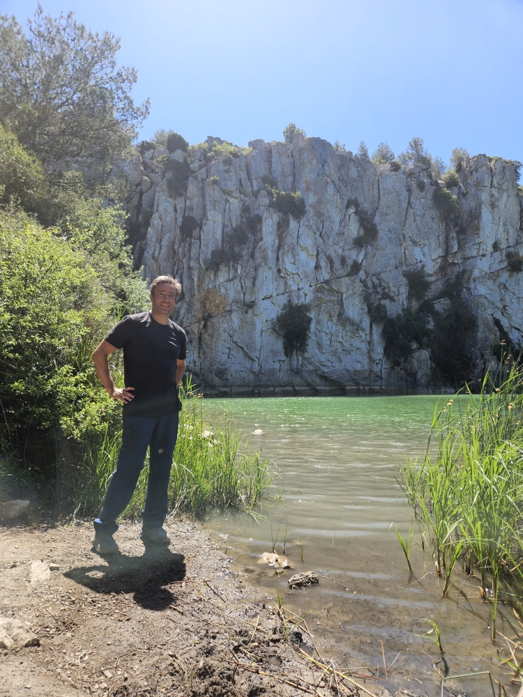 Angel an einem türkisfarbenen Bergsee mit weißen Kalksteinfelsen im Massif de la Clape